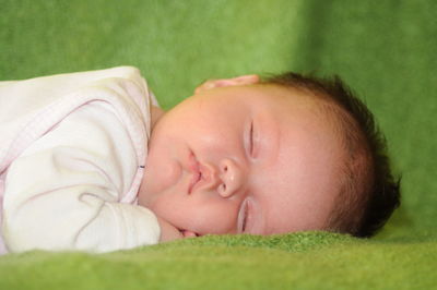 Close-up of cute baby girl sleeping on blanket