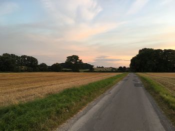 Road amidst field against sky