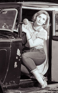 Attractive pin-up woman posing in a vintage car. in black and white technique, film noir style.