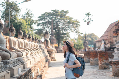 Side view of woman standing by statues in temple