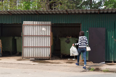 Woman housewife throws garbage into a container in the yard of the house. person