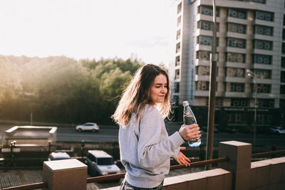 Young woman with arms raised standing in city