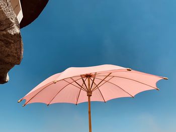 Low angle view of umbrella against clear blue sky