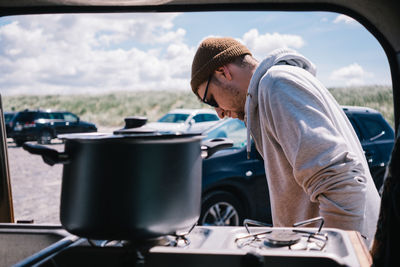 Man wearing sunglasses preparing food in car outdoors