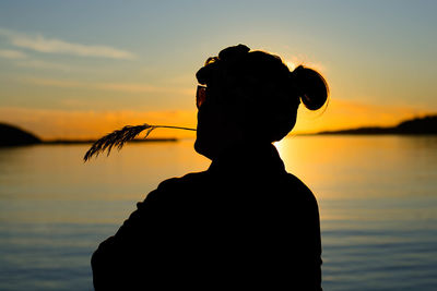 Silhouette woman standing by sea against sky during sunset