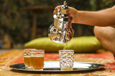 Close-up of hand pouring wine in glass on table