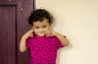 Portrait of cute girl standing against wall at home