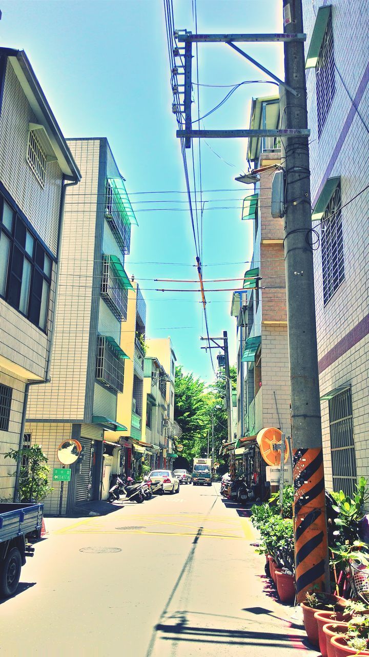 building exterior, architecture, built structure, the way forward, street, clear sky, residential building, residential structure, house, power line, sky, city, diminishing perspective, transportation, blue, sunlight, day, building, electricity pylon, outdoors