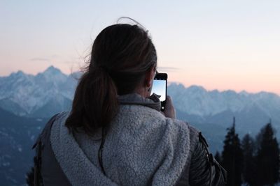 Rear view of woman photographing mountains through phone