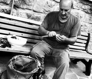 Tilt shot of man peeling mushrooms while sitting on bench