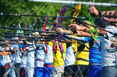 People holding bow and arrow while standing on land