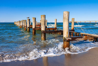 Wooden posts on beach against clear sky