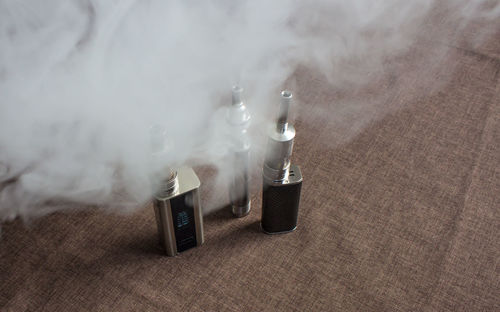 High angle view of electronic cigarettes on table with smoke