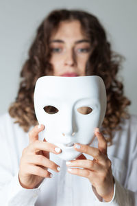 Woman holding mask against white background