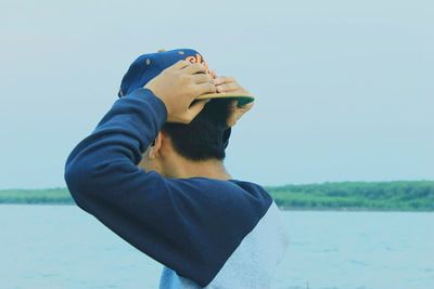 Close-up of boy standing by lake against clear sky