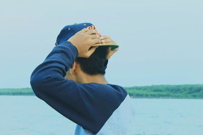 Close-up of boy standing by lake against clear sky