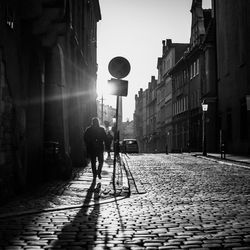 Rear view of man walking on footpath in city