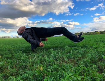 Full length of man levitating on field against sky