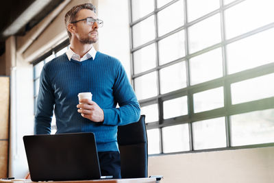 Businessman holding coffee cup looking away