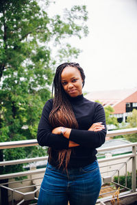 Portrait of woman with braided hair standing by railing