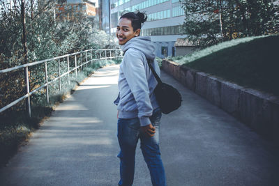 Side view of young man looking away while standing on footpath