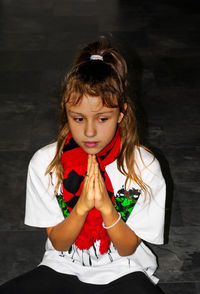 A girl in a sports outfit prays that her favorite team will win.