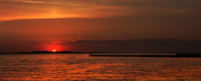 Scenic view of sea against dramatic sky during sunset