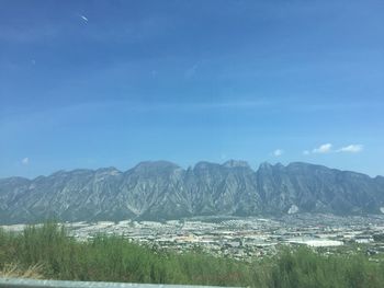 Scenic view of sea and mountains against blue sky