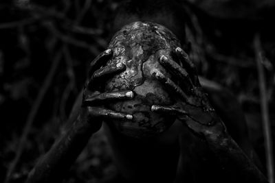 Close-up of messy man holding animal skull outdoors