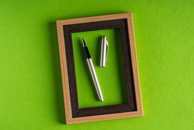 High angle view of pen on paper against green background