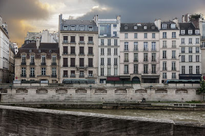 Buildings in city against cloudy sky