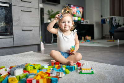 Cute girl playing with multi colored toy at home