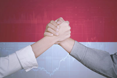 Cropped image of women holding hands against chart