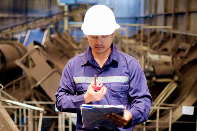 Engineer looking at walkie-talkie while standing in workshop