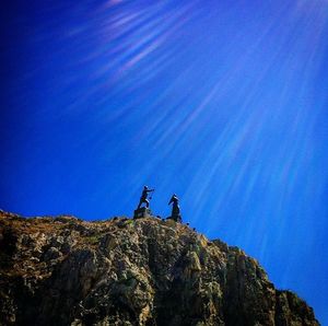 Low angle view of rocks against blue sky