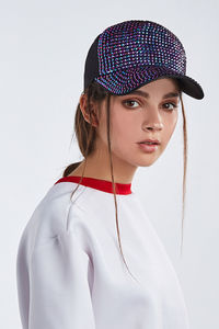 Portrait of young woman wearing hat against white background