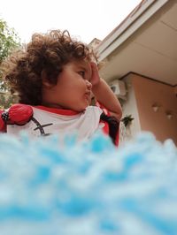 Low angle view of girl looking away standing by house