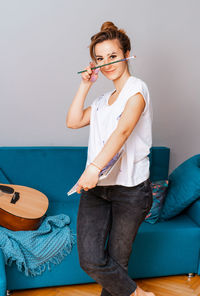 Portrait of smiling young woman standing against wall