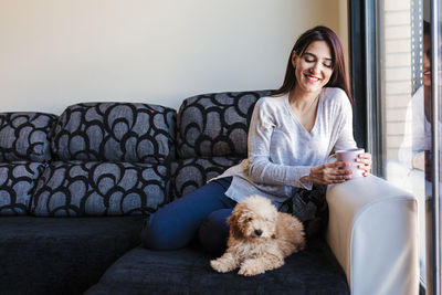 Young woman sitting on sofa at home