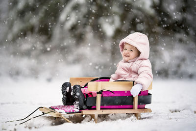 Cute boy sitting on snow covered landscape during winter