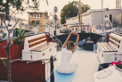 Woman doing stretching exercise on houseboat at harbor