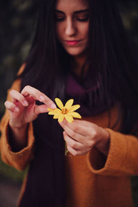 Smiling woman holding flower standing outdoors