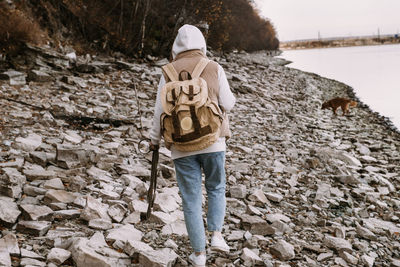 Young woman and dog retriever walks on river shore at autumn season