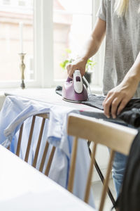 Cropped image of teenager ironing clothes at home