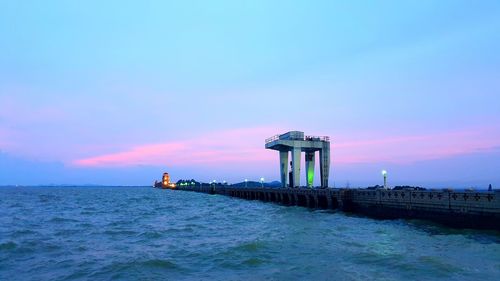 Lighthouse by sea against sky during sunset