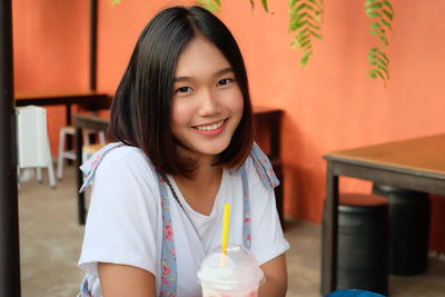 Portrait of smiling young woman sitting at sidewalk cafe