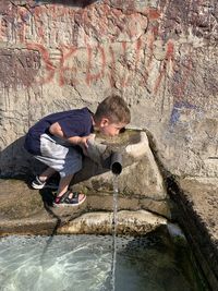 Full length of boy drinking water at fountain