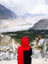 Rear view of woman looking at valley against cloudy sky