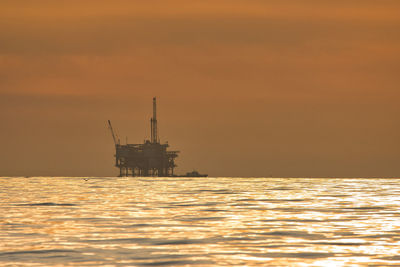 Silhouette ship in sea against sky during sunset