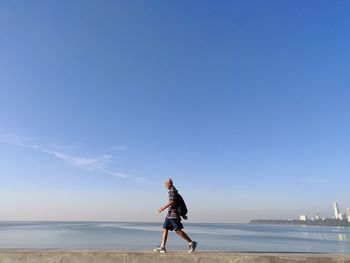 Man walking at beach against sky